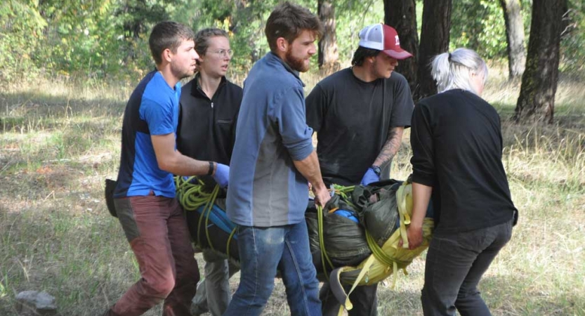 five people carry someone during a wilderness first responder course
